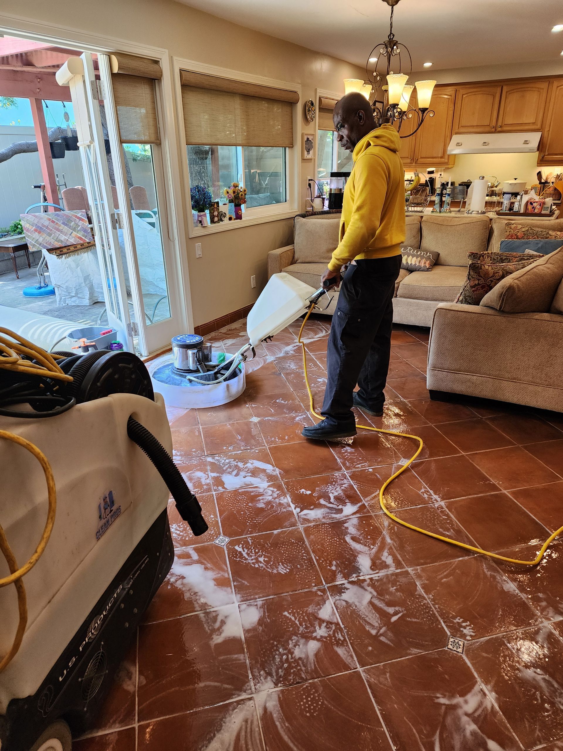 Person vacuuming a tiled living room with dust-covered floor and furniture after a renovation