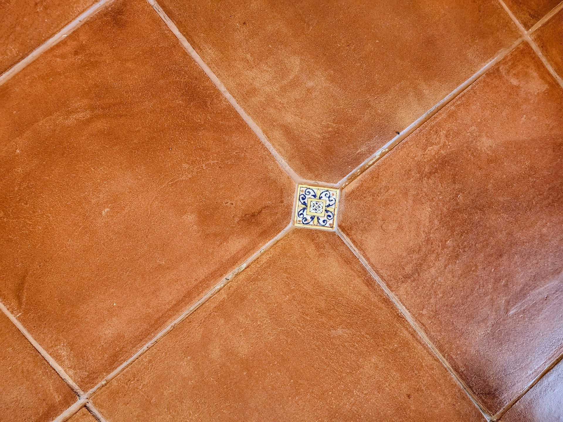 Orange-brown tiled floor with diagonal grout lines and a small decorative center tile.