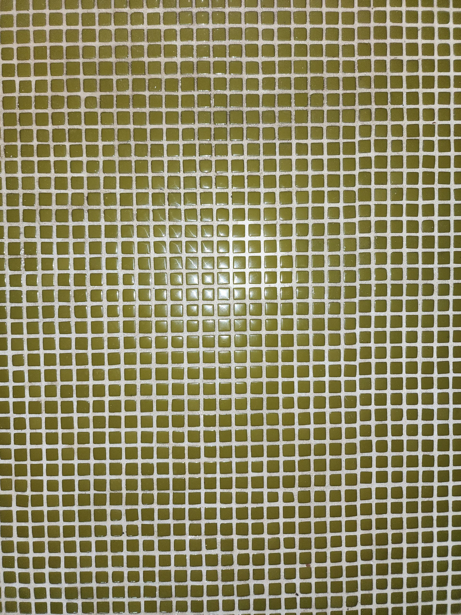 Close-up of a beige and white mosaic tile pattern with a bright reflection in the center