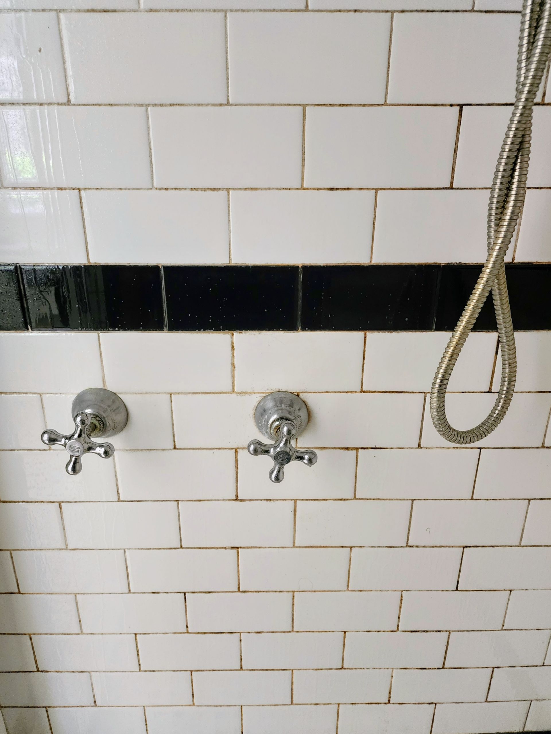 Small tiled bathroom wall with a round shower drain near the top center.
