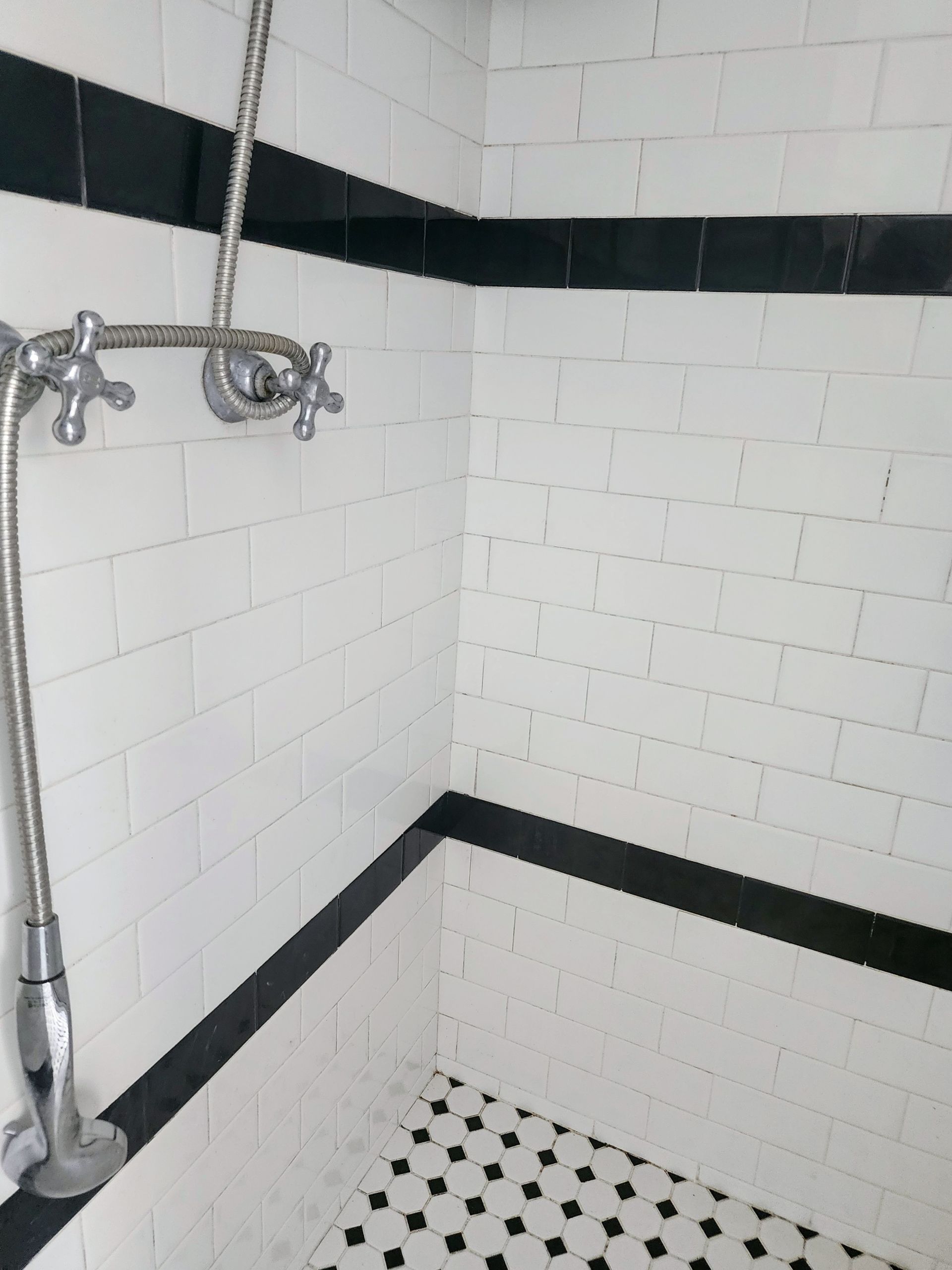 Black-and-white tiled shower with chrome fixtures and a handheld showerhead