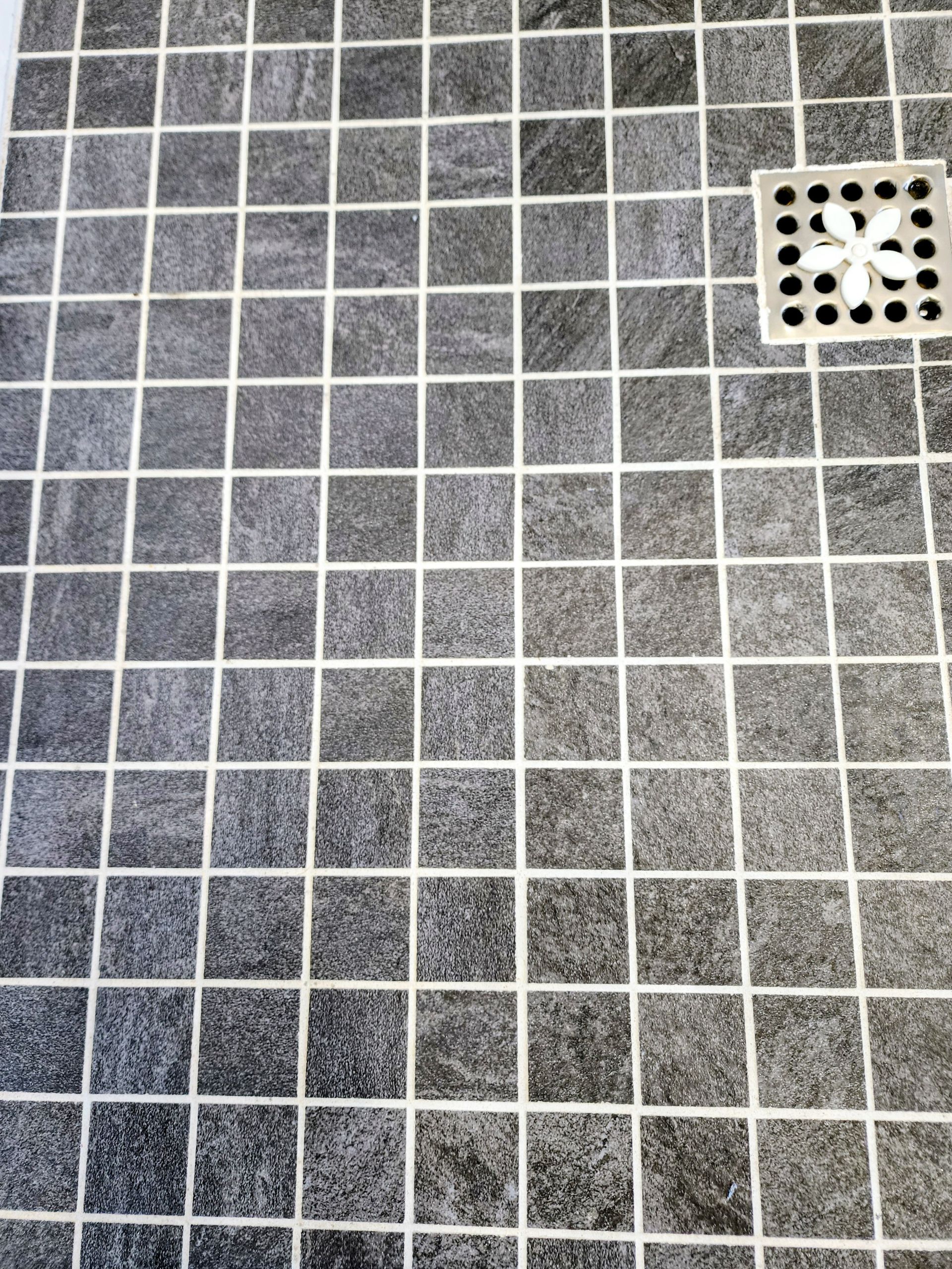 Gray tiled floor with a square drain cover in the upper right corner