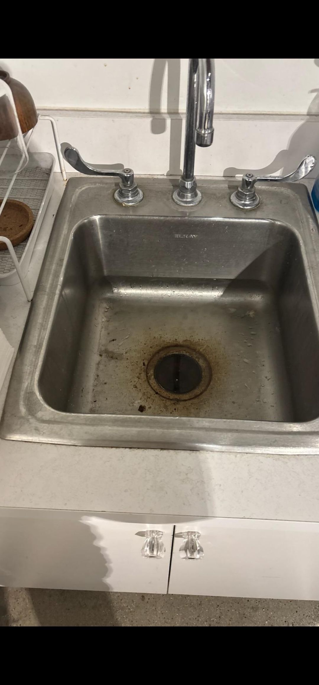 Stainless steel kitchen sink with a faucet and dirty basin, showing a clogged drain.