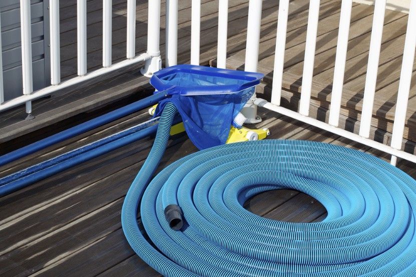 A Blue Hose is Sitting on a Wooden Deck Next to a Vacuum Cleaner — Fannie Bay Pool Shop in Cullen Bay, NT