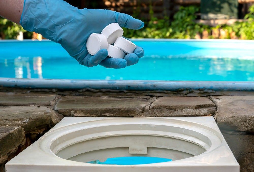 A Person is Pouring Chlorine Tablets Into a Pool — Fannie Bay Pool Shop in Larrakeyah, NT