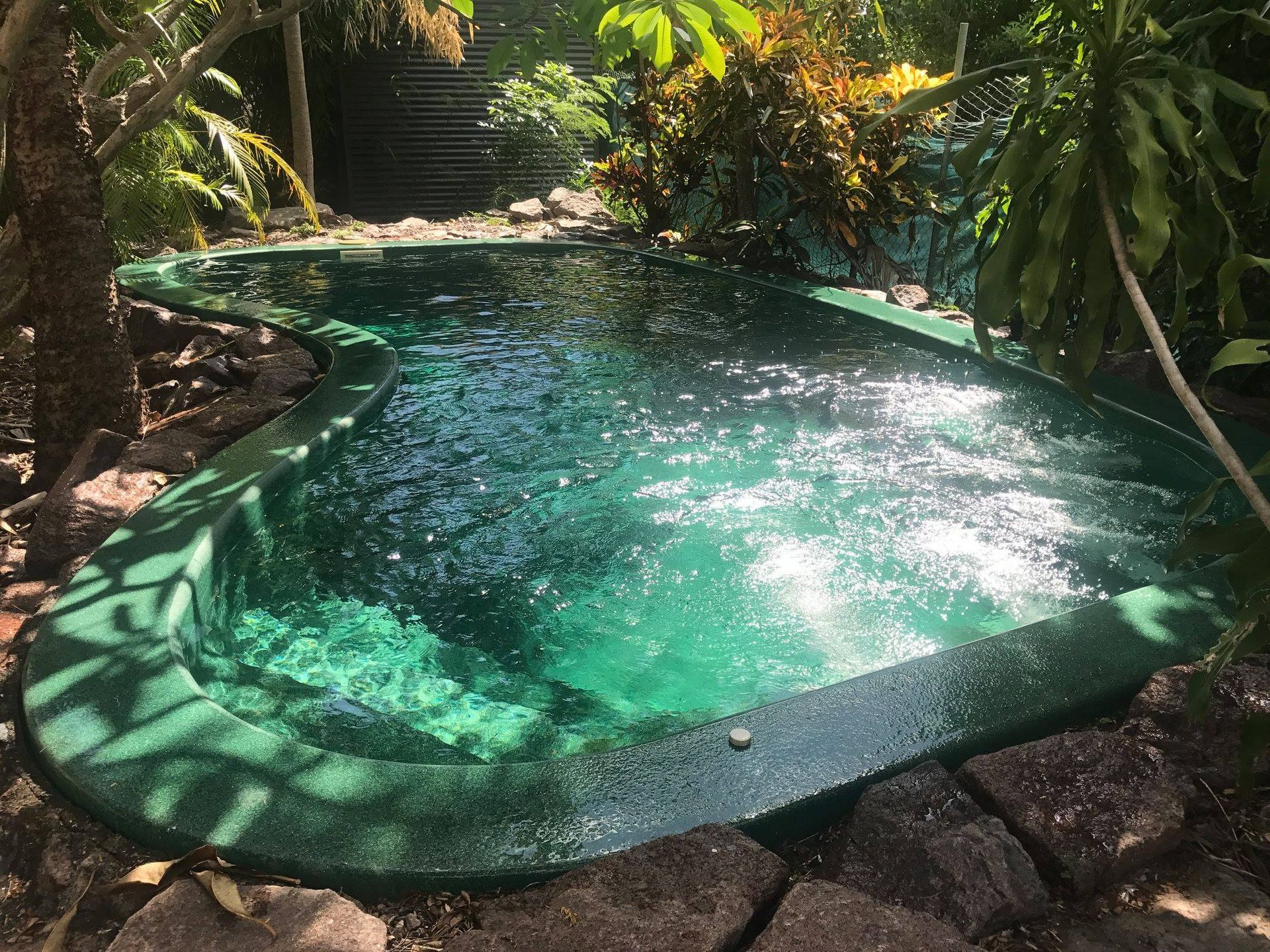 A Large Clean Swimming Pool Surrounded by Trees and Rocks — Fannie Bay Pool Shop in Winnellie, NT