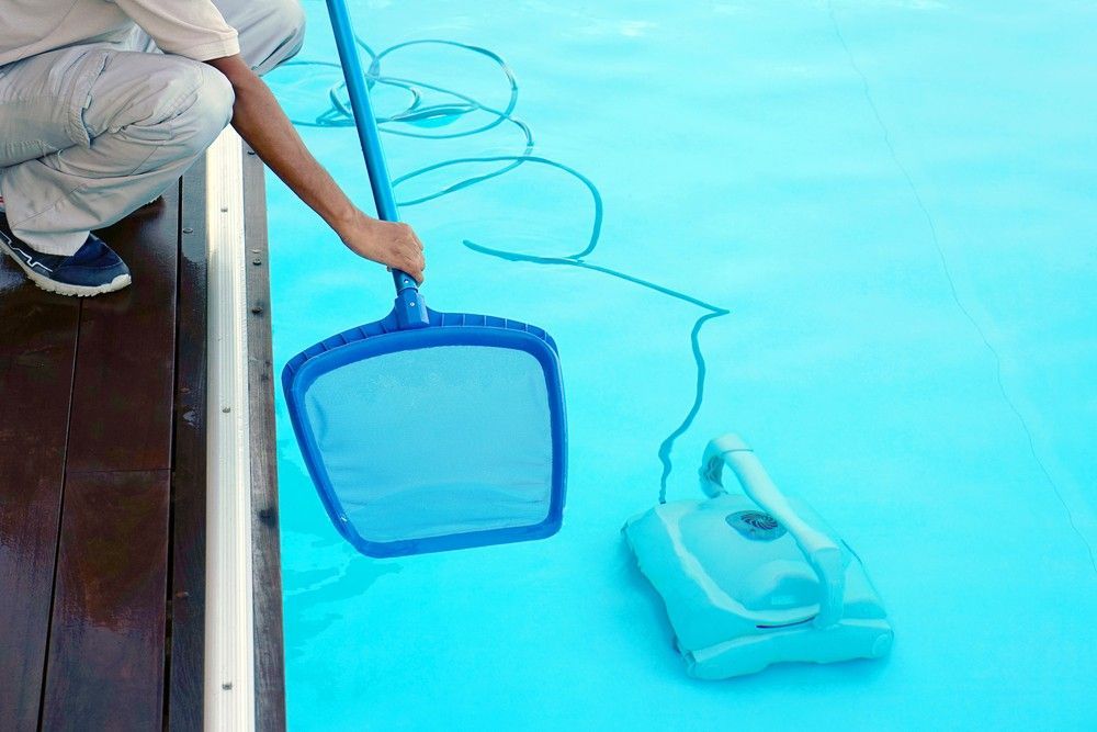 A Man is Cleaning a Swimming Pool With a Cleaner — Fannie Bay Pool Shop in Bayview, NT