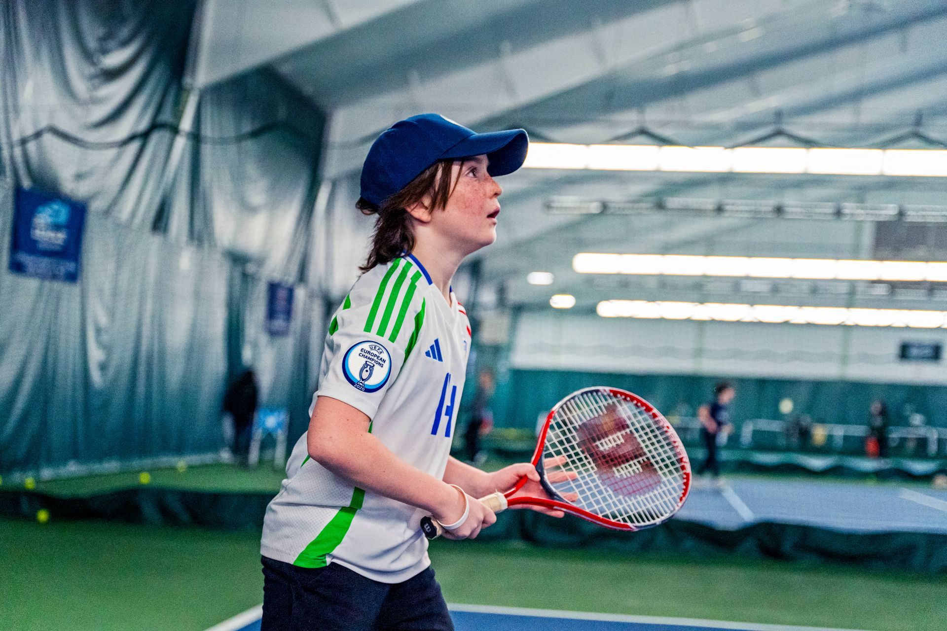 A young boy is holding a tennis racquet on a tennis court.