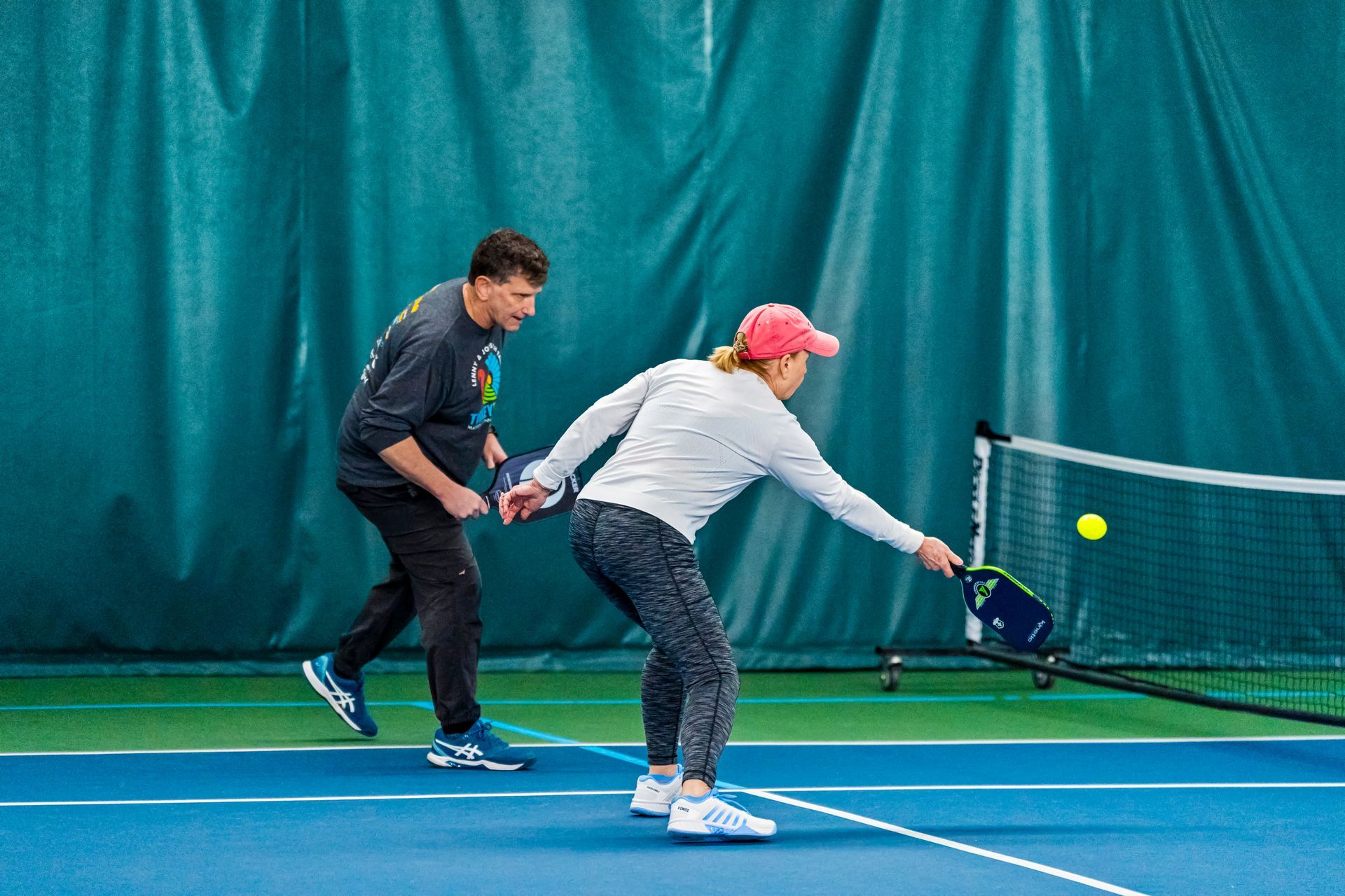 A man and a woman are playing tennis on a tennis court.