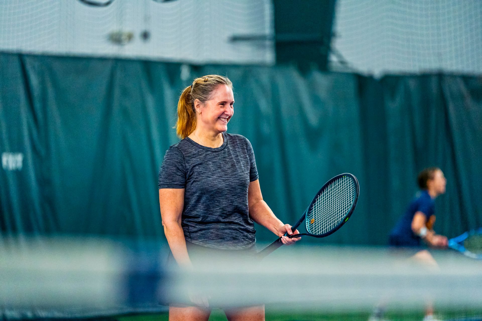 A woman is holding a tennis racquet on a tennis court.