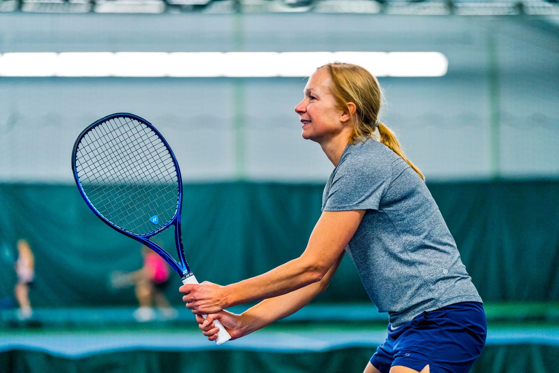 A woman is holding a tennis racquet on a tennis court.