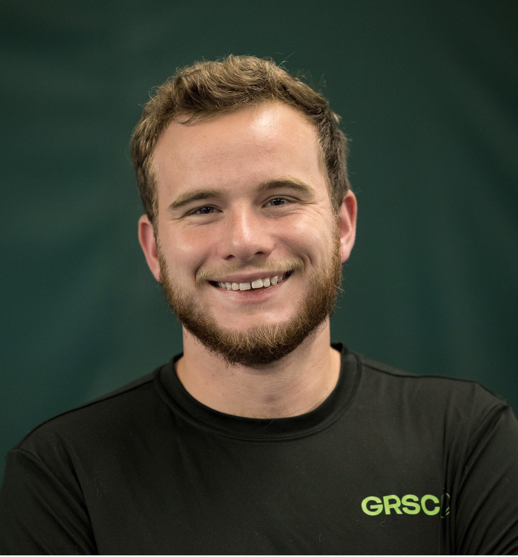 A man with a beard is wearing a black shirt that says grsc