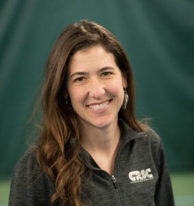 A woman wearing a gray jacket is smiling for the camera.