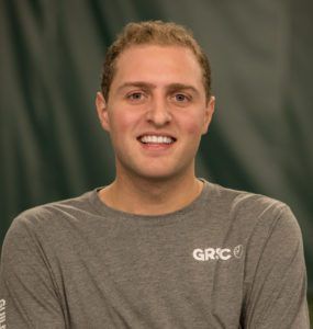A woman wearing a gray shirt is smiling for the camera.