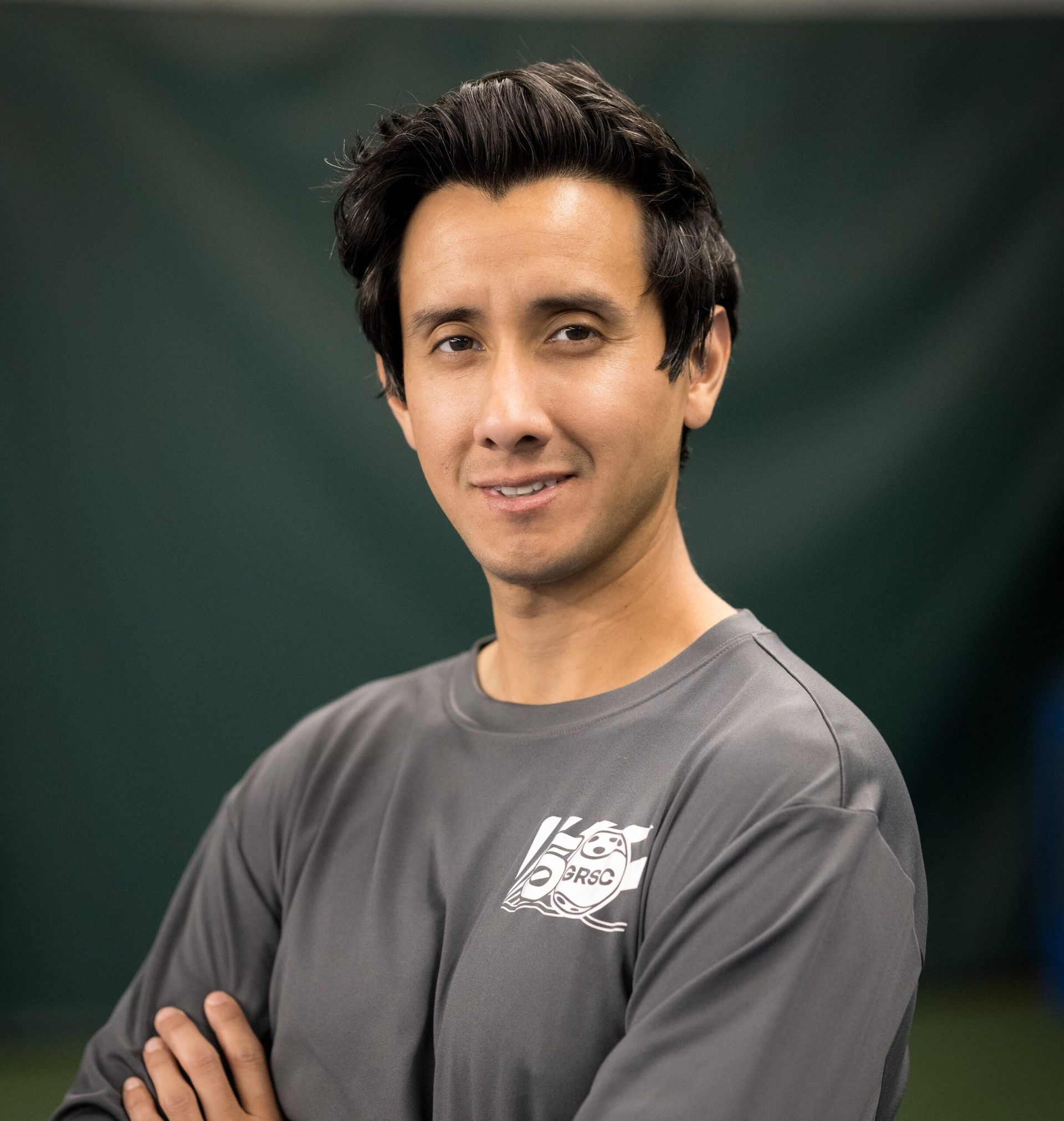 A man with his arms crossed is wearing a gray shirt