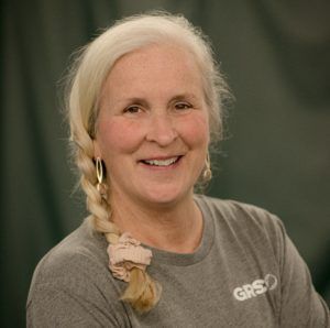 A woman with long brown hair is smiling and wearing a black shirt