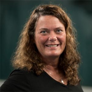 A woman with long brown hair is smiling and wearing a black shirt