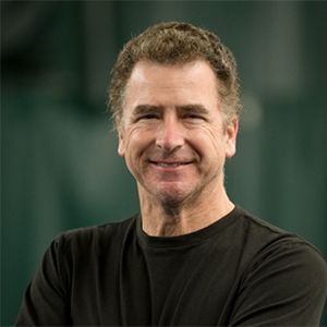 A woman wearing a gray shirt is smiling for the camera.