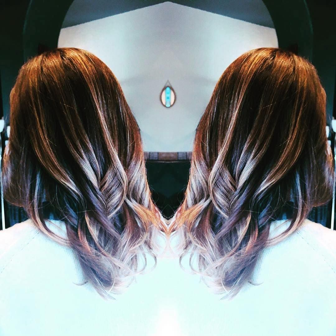 A mirror-image reflection of a person's shoulder-length brown hair with highlighted ends, styled in soft waves.