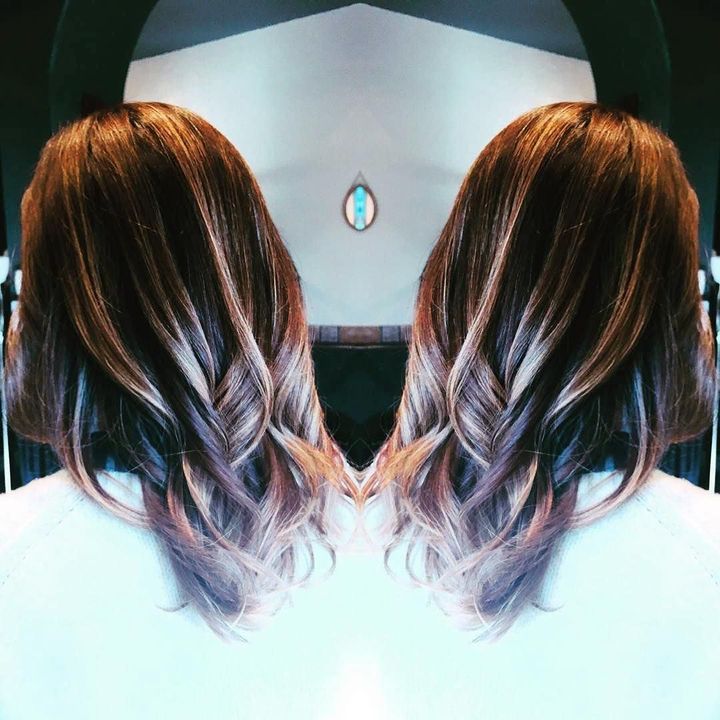 A mirror-image reflection of a person's shoulder-length brown hair with highlighted ends, styled in soft waves.