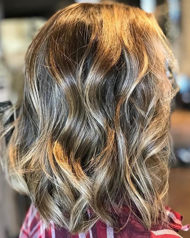 Shoulder-length hair with brown and blonde highlights styled in loose, soft waves.