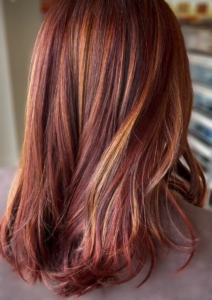 Shoulder-length hair with a multi-tonal auburn base featuring light golden brown highlights.