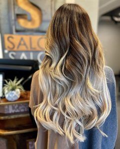 Long, wavy hair showcasing a brown-to-blonde ombre color transition in a salon setting.