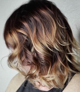 Shoulder-length, wavy hair with a balayage color transition from dark brown roots to blonde ends.