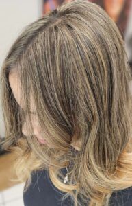 A woman with shoulder-length, layered hair styled in light brown and blonde highlights, viewed from above.