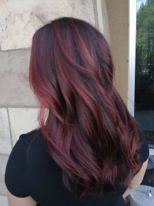 Long, wavy dark hair with deep red and burgundy highlights, viewed from behind.