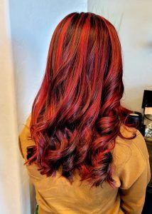 Back view of long, wavy hair with vibrant red and dark brown highlights.