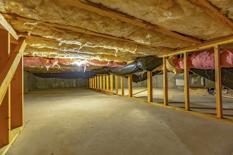 A basement under construction with insulation and pipes.