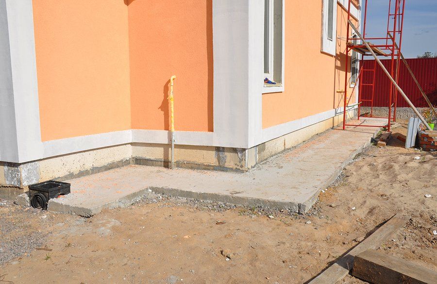 A house is being built with a concrete walkway in front of it.