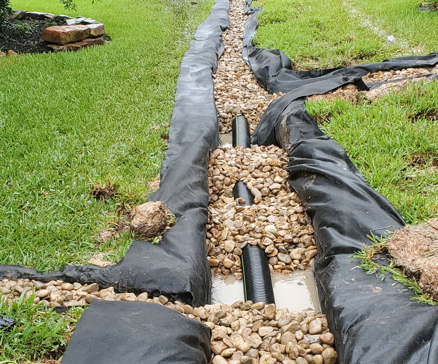 A French drain system under construction with gravel and pipes for effective water drainage.