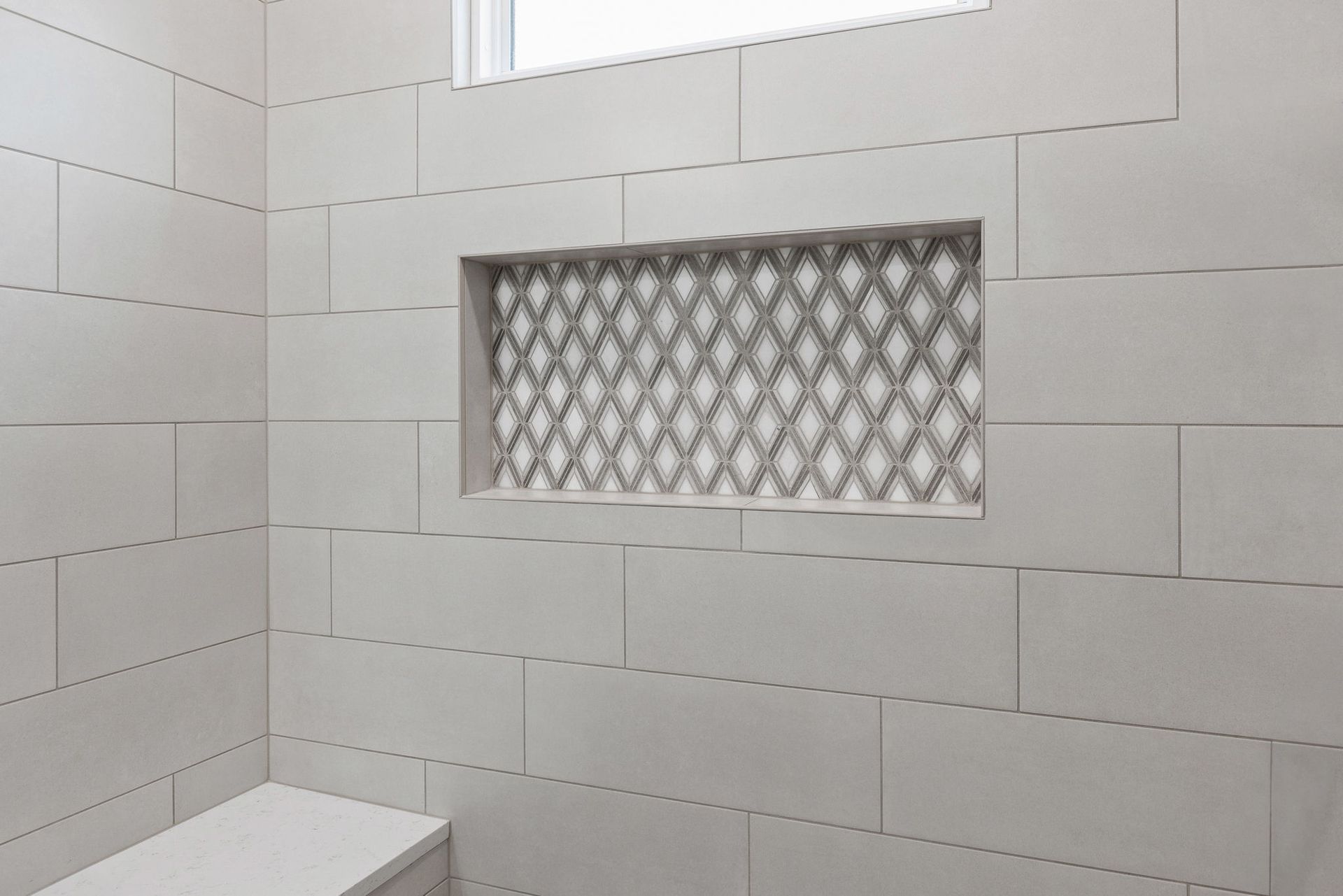A bathroom with white tiles and a window.