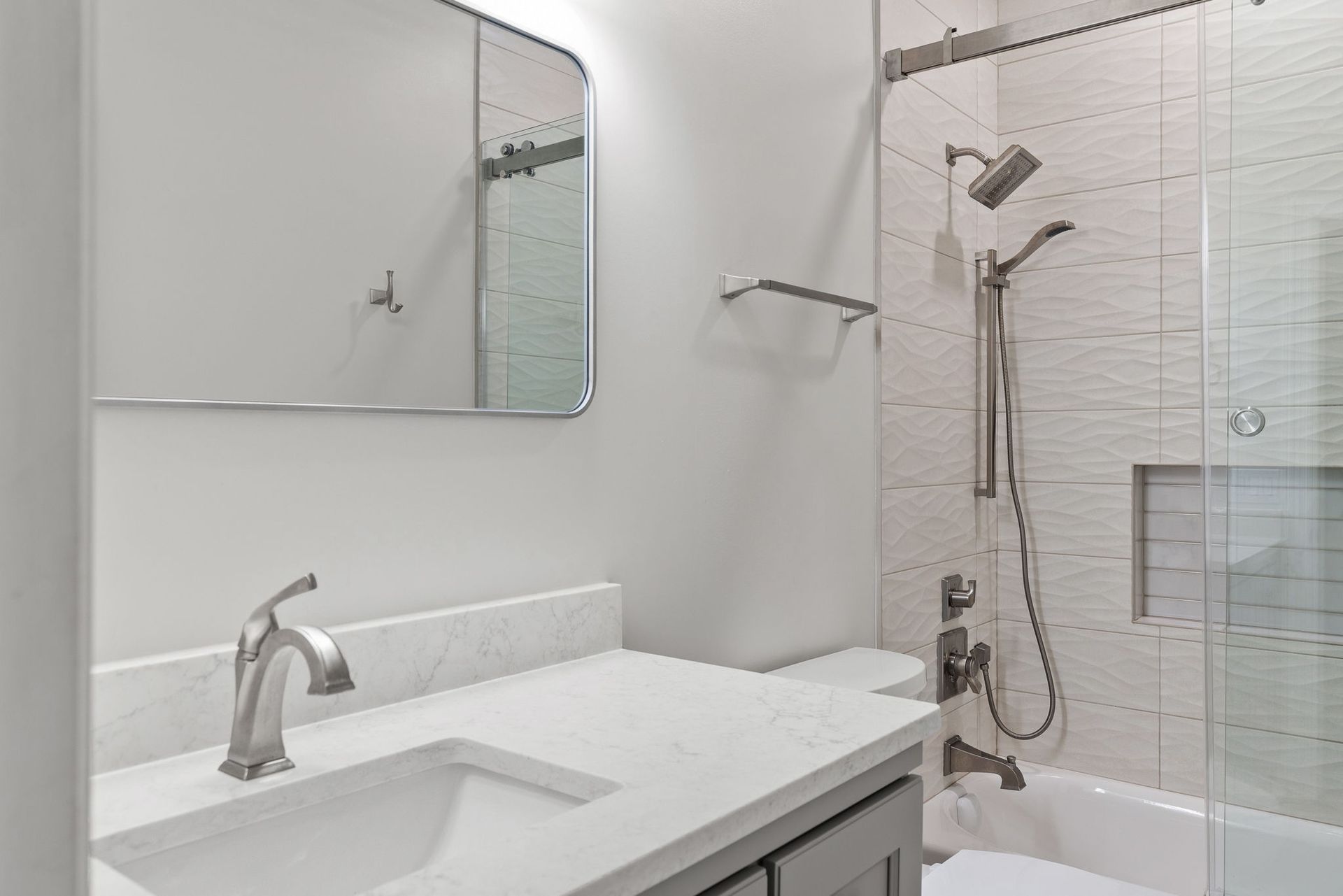A bathroom with a sink , tub , shower and mirror.