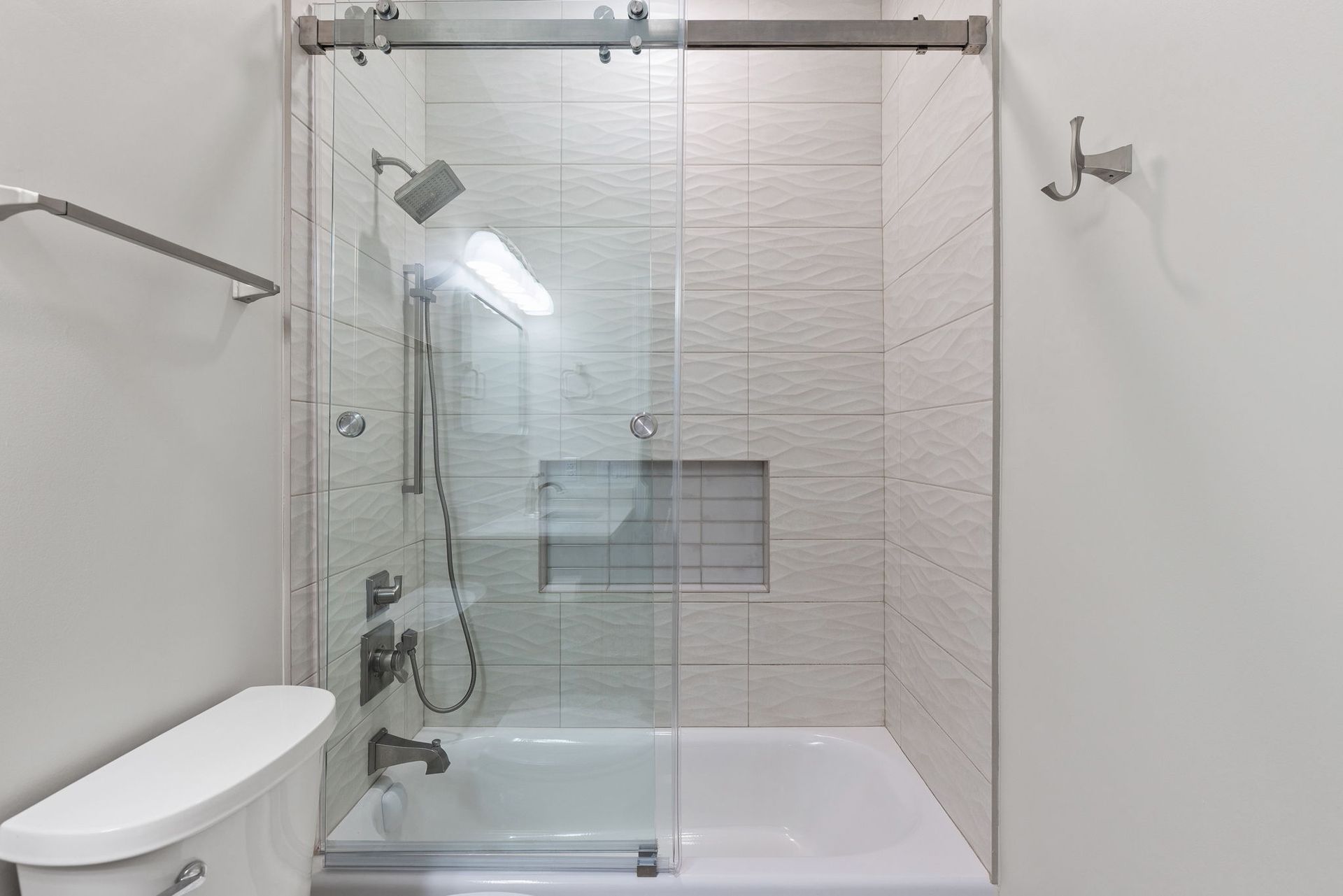 A bathroom with a tub , toilet , shower and sliding glass door.