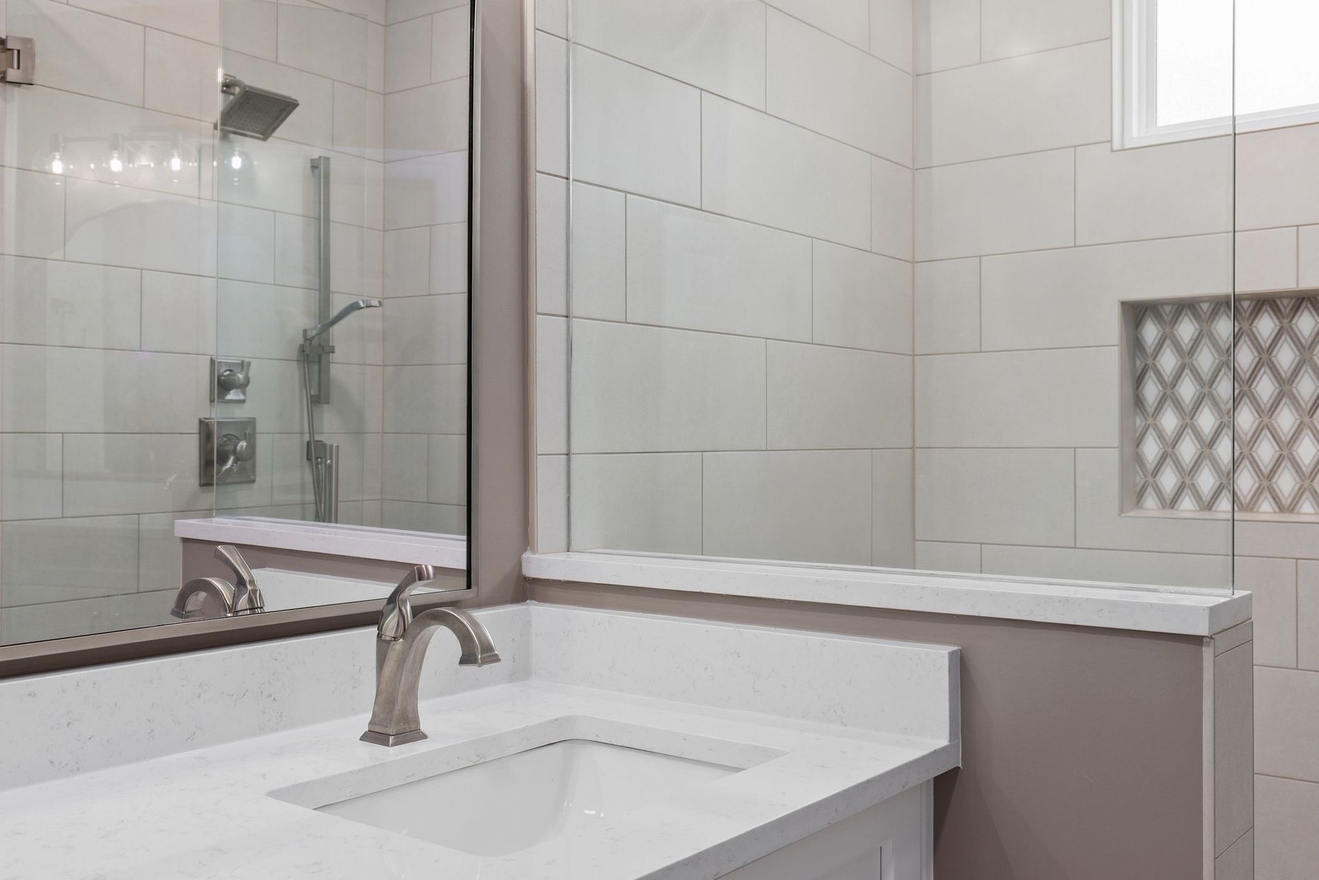 A bathroom with a sink , mirror and shower.