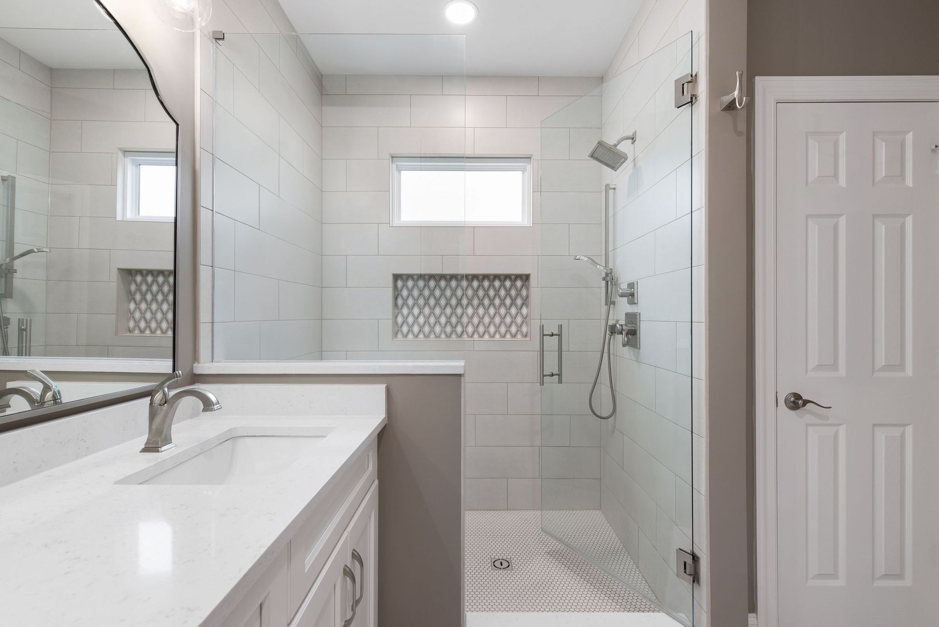 A bathroom with a walk in shower , sink and mirror.