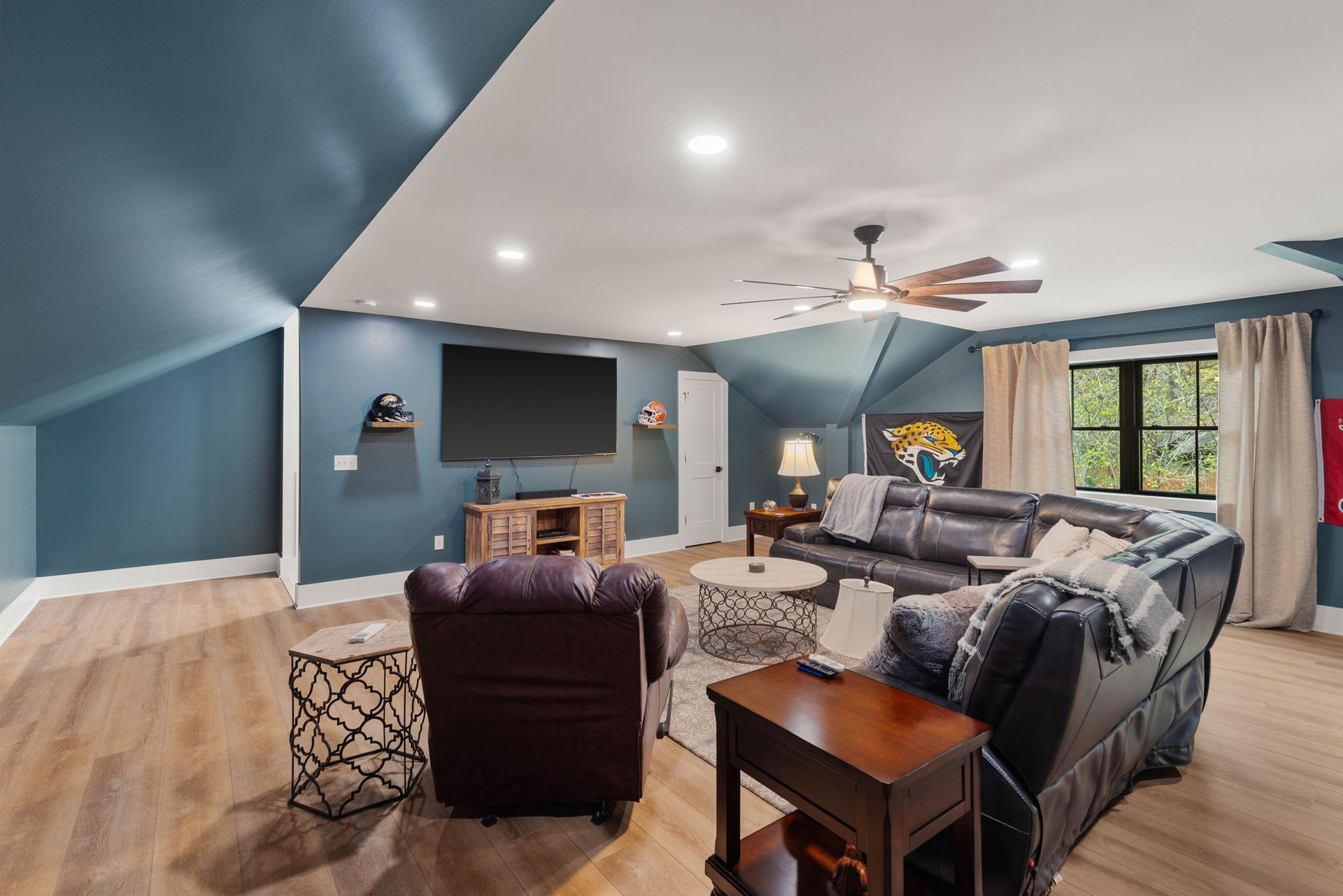 A living room with a couch , chairs , a television and a ceiling fan.