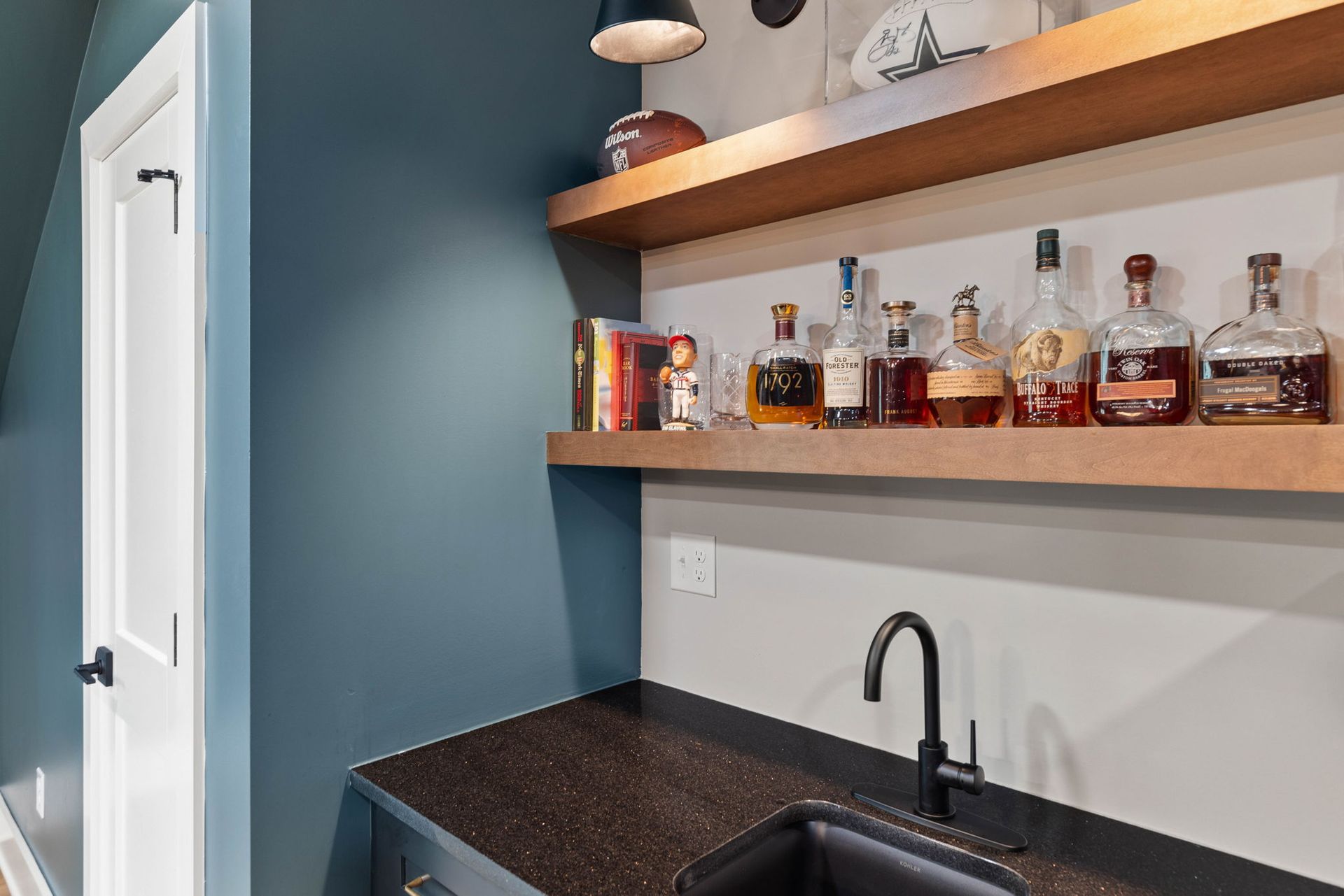 A kitchen with a sink and shelves filled with bottles of alcohol.