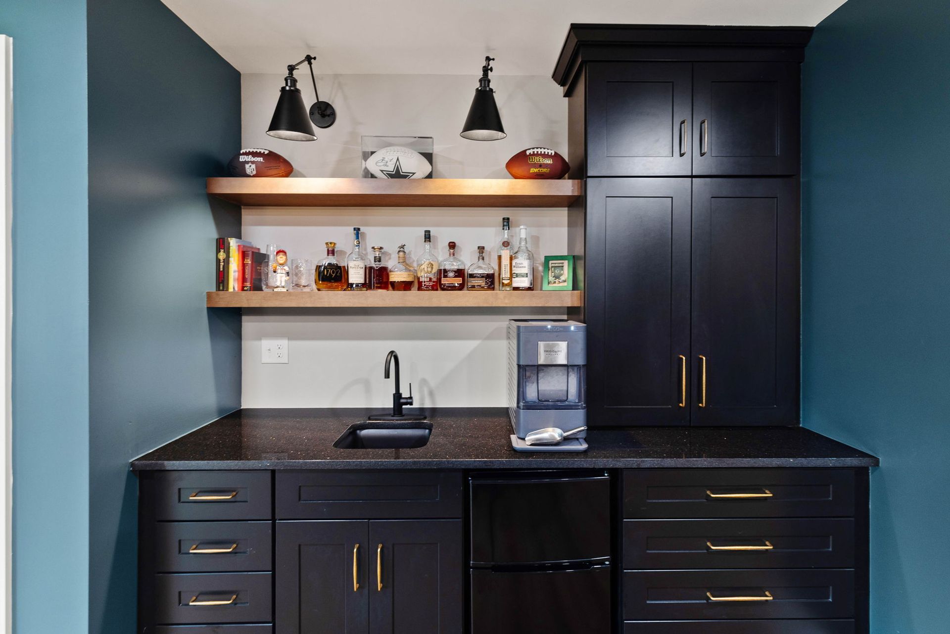 A kitchen with black cabinets , a sink , and a bar.
