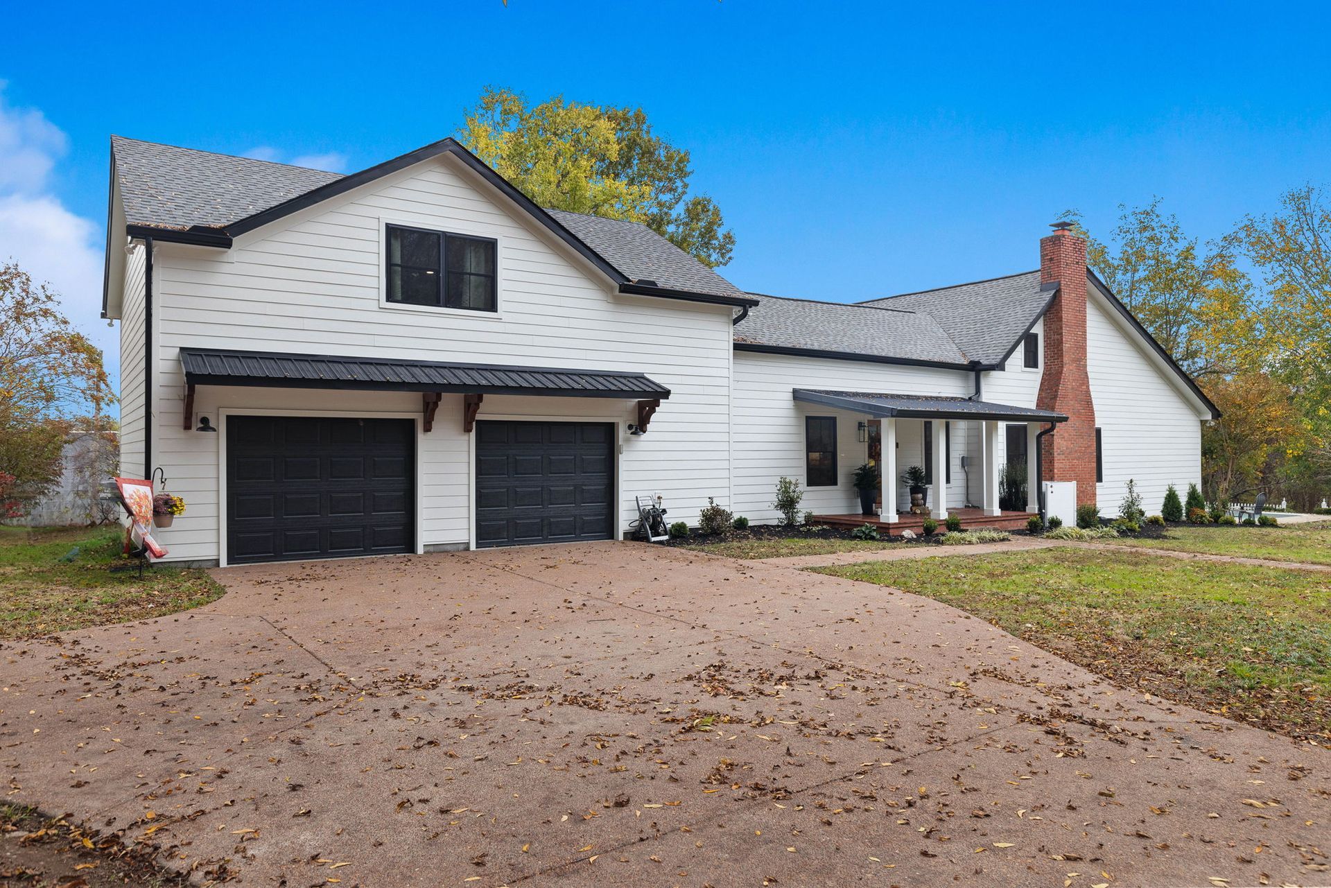 A large white house with two garages and a porch.