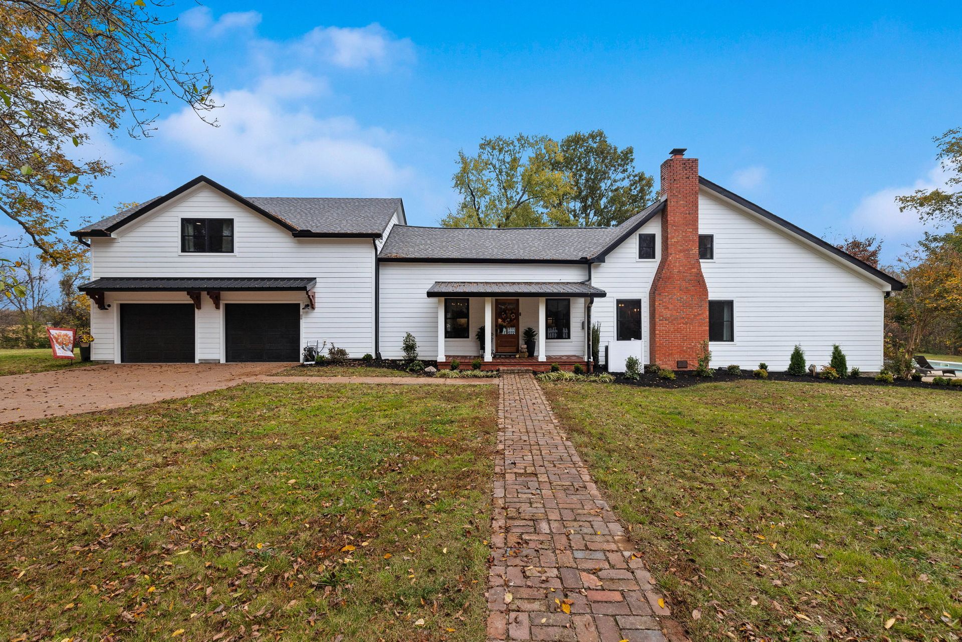 A large white house with a brick walkway leading to it.