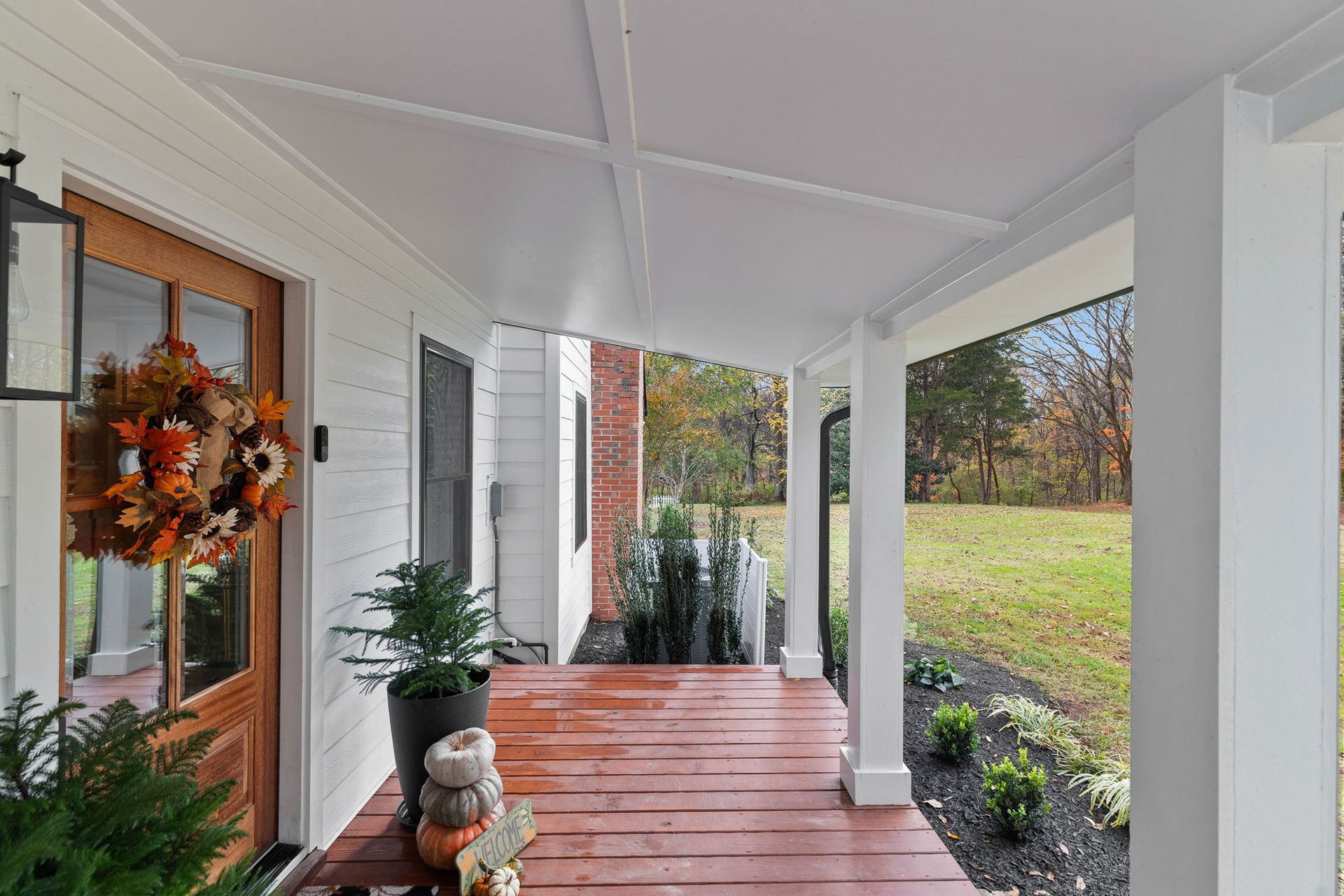 A porch with a wooden floor and a wreath on the door of a house.