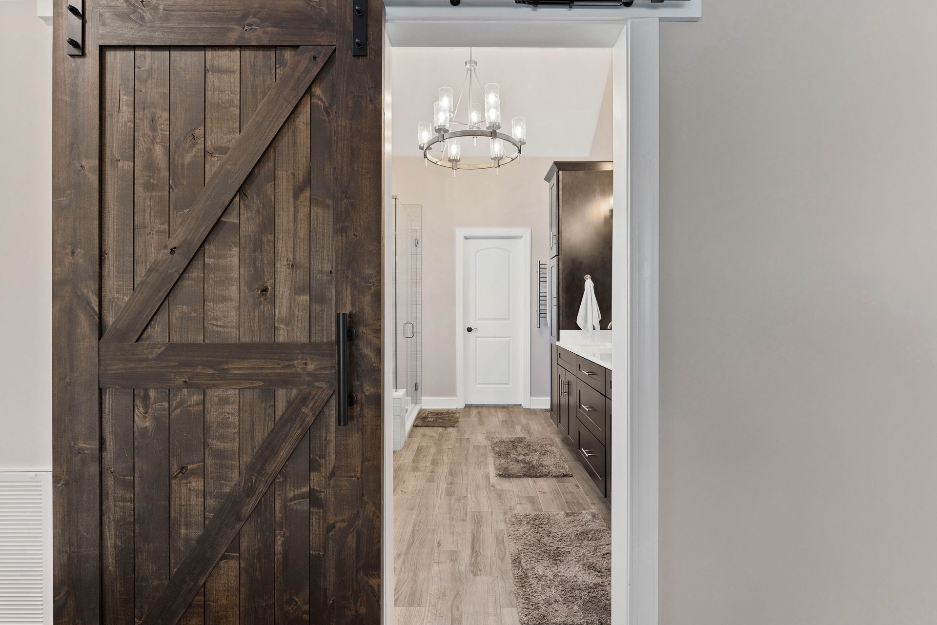 A bathroom with a sliding barn door leading to it.