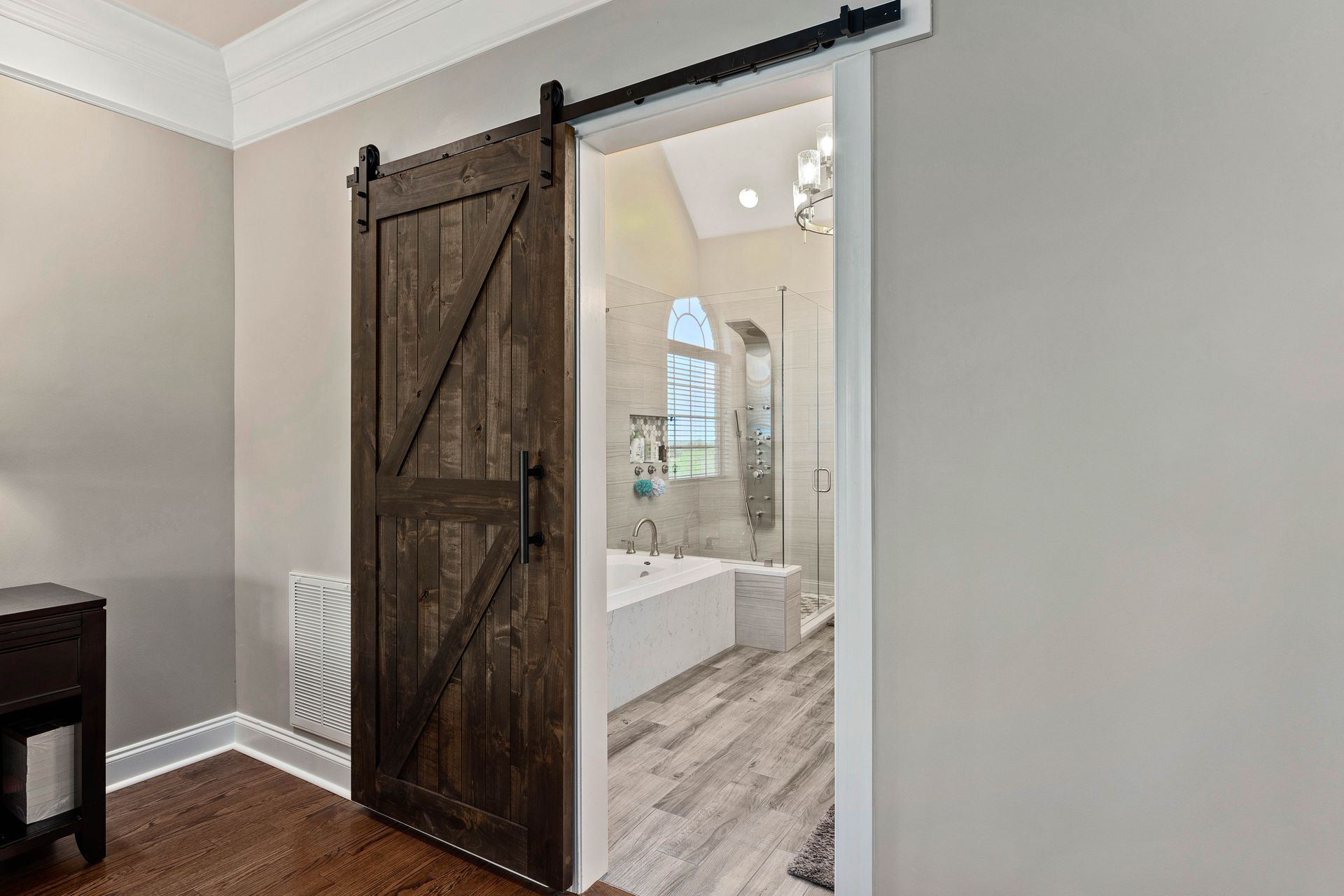 A bedroom with a sliding barn door leading to a bathroom.