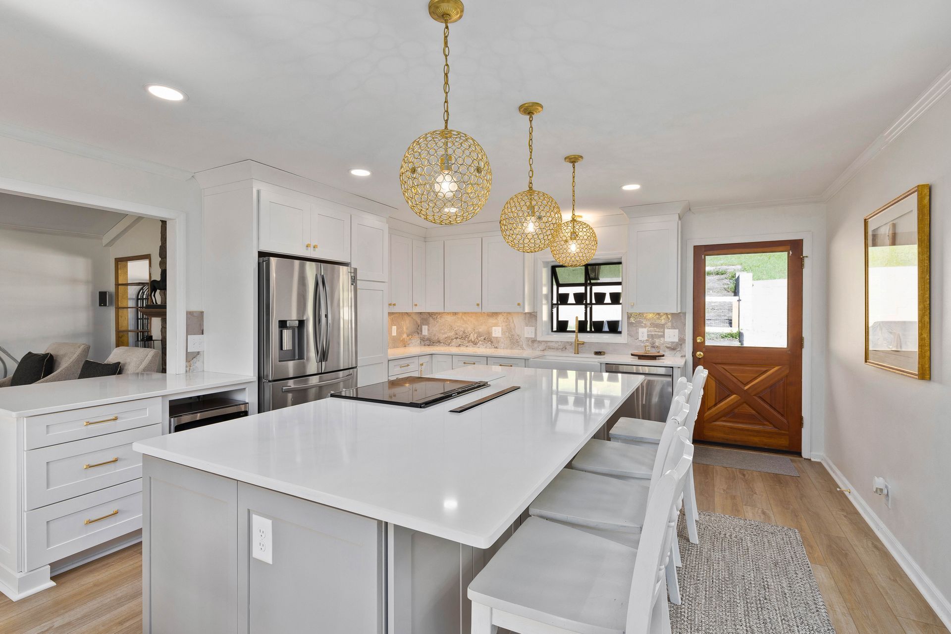 A kitchen with white cabinets , stainless steel appliances , and a large island.