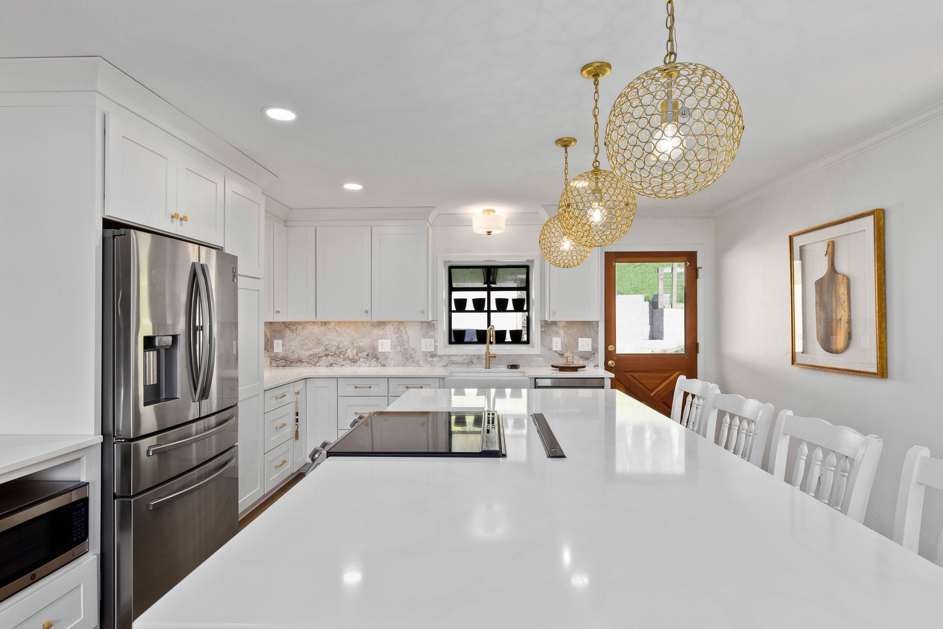A kitchen with white cabinets , stainless steel appliances , and a large island.