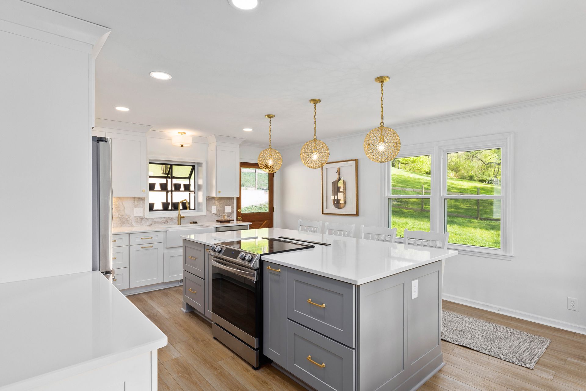 A kitchen with white cabinets , stainless steel appliances , and a large island.